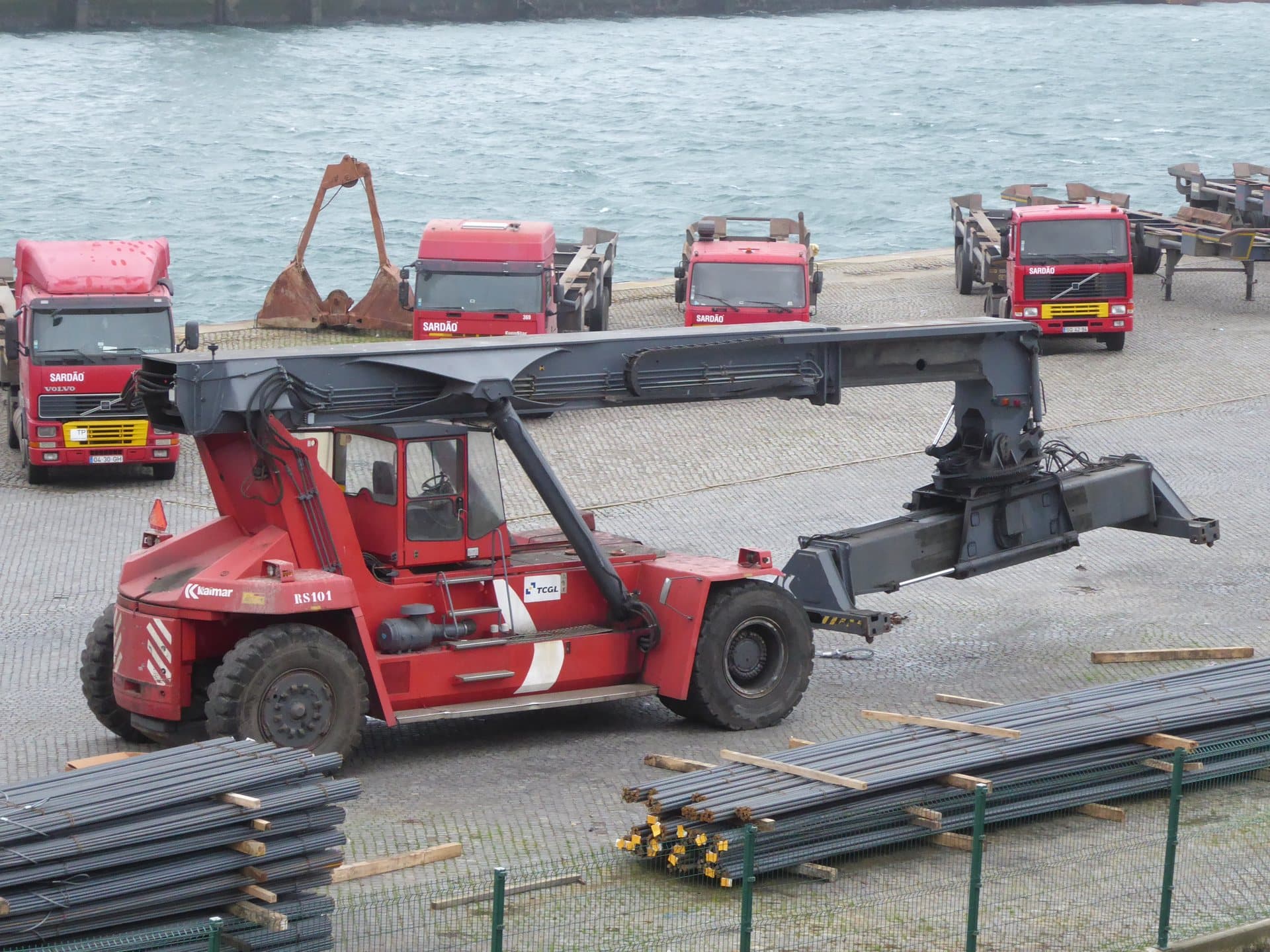 Heavy reach stacker handler moving containers in shipping yard